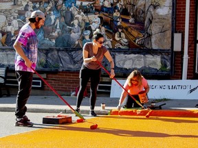 Felipe Golod, Emmalyn Rynard and Deb Keogh put the first layer of paint down on the orange crosswalk in downtown Gananoque on Monday.