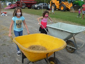 Peyton and Kamryn Aucoin take a third run at the Farmers Olympics course at the Spencerville Fair on Saturday. In addition to a wheelbarrow push, the event included an egg toss and sack race.
Tim Ruhnke/The Recorder and Times