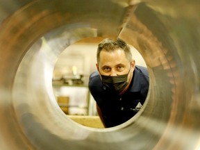 Lorne Phillips, director of operations at DB Piping (Douglas Barwick), peers through one of the products at the Brockville plant as management and staff mark the California Avenue facility's 50th anniversary on Thursday. RONALD ZAJAC/The Recorder and Times