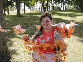 Jennifer Kehoe, co-founder of the Indigenous Family Circle for students and families in Limestone District School Board, shows off a handful of the 800 tiny orange shirts made and decorated by local elementary students that will go on display at the sacred fire at 817 Division St. in Kingston, Ont., on Thursday, Sept. 30, 2021.