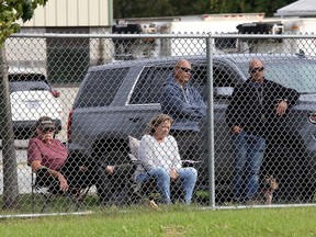 Spectators watch from outside the fence at CaraCo Home Field as the Frontenac Falcons and Holy Cross Crusaders play a Kingston Area Secondary Schools Athletic Association field hockey game on Monday. Spectators are currently banned from sitting in the stands at indoor and outdoor games.