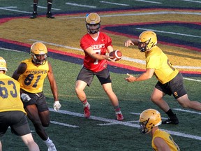 Quarterback James Keenan hands off the ball as the offence works on plays during a Queen’s Gaels football practice at Richardson Stadium in Kingston on Tuesday. Ian MacAlpine