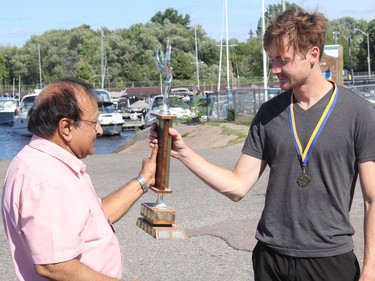 Kiwanian Raghavan Vijay presents the winner of the Kiwanis Ottawa River Swim, Brady Risteen, with the trophy.