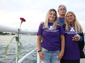 Brienne, left, George and Laurie Hicks stand by a carnation tied in memory of Ryan Hicks at Sarnia's waterfront Tuesday. An evening memorial was held for International Overdose Awareness Day. (Tyler Kula/ The Observer)