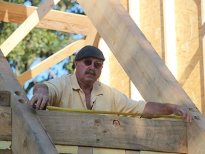 Mark Gagnier takes a measurement while volunteering on a Seaway Kiwanis Club project building a new log cabin near the Children's Animal Farm in Sarnia's Canatara Park.
