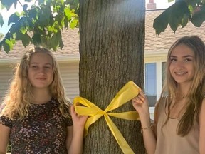 Addison Compagnion, left, and Amy Fraser tie a yellow around a tree for Friday's World Suicide Prevention Day.