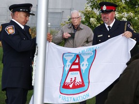Sarnia firefighter and Aamjiwnaang First Nation member Brian Bois, left, and Sarnia Police Const.  and Walpole Island First Nation member Uriah Dodge raises the Aamjiwnaang flag at the First Nations Flag Plaza in Sarnia Sept. 25, 2021.