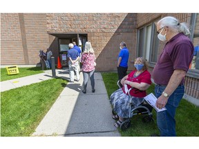 Carolyn and Robert Harrington wait in the shade as voters line up Friday Sept. 10, 2021, outside Westview Baptist Church on Wonderland Road South. The church is an advance polling site for the London West riding. (Mike Hensen/The London Free Press)