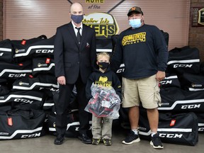 From left to right, Paul Sebastian from the OMHA board of directors, under-7 Shallow Lake Laker Michael Cooper, and Scott McManus from the Shallow Lake Lakers Minor Hockey Association pose in front of 35 bags of hockey gear recently donated to the program to help families get their children on the ice. Greg Cowan/The Sun Times