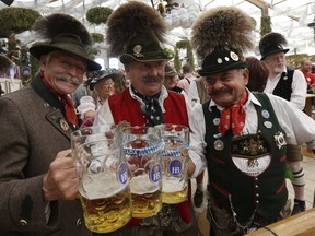 Traditionally dressed Bavarian men raise their steins and enjoy a sunny day of the famous Bavarian "Oktoberfest" beer festival in Munich, southern Germany, Tuesday, Sept. 25, 2012. (AP Photo/Matthias Schrader)