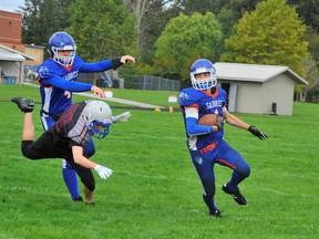 Joe Thwaites of the Simcoe Sabres gets a block from quarterback Dylan Courrier as he moves the ball upfield against the Holy Trinity Titans Friday. The Sabres dropped another close one, this time by a score of 13-12 at Holy Trinity. – Monte Sonnenberg