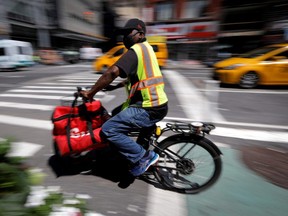 A rider for Grubhub food delivery service rides a bicycle during a delivery in midtown Manhattan in New York City. (REUTERS/Mike Segar/File Photo)