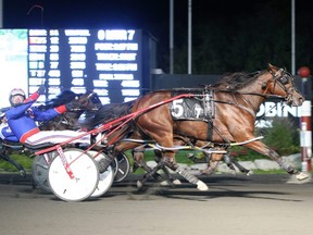 Driver Sylvain Filion salutes Woodbine Mohawk Park announcer Ken Middleton as he steers Bob Loblaw to a 1:53 victory in the $225,000 Super Final for two-year-old pacing colts in Milton, Ont., on Saturday, Oct. 16, 2021. (New Image Media Photo)