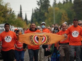 Dallas Fisher (left), Montgomery Withawick singing, and Craig Lavand holding onto a GCT3 flag and leading the march from the Cecilia Jeffrey IRS Memorial Site on September 30.