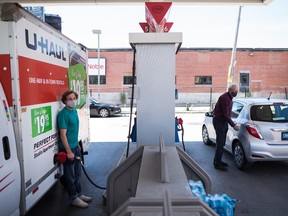 People pump gas into their vehicles at a Esso station in Toronto on Tuesday, June 15, 2021.