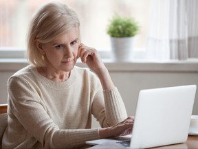 Thoughtful frustrated woman sitting at table near laptop