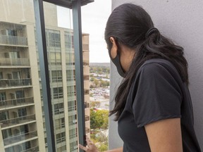 Fatema looks down to a memorial to her daughter through the gap in their balcony 20-stories up. The tot fell earlier this month. (Mike Hensen/The London Free Press)