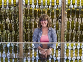 Mary MacDonald, co-owner of Stanners Vineyard and local artist sits at a table in front of her found-object art installation Friday in Prince Edward County. ALEX FILIPE