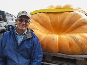 Todd Kline sits beside Hail Mary, a 1472-pound pumpkin he grew which took home first prize at the 2021 Pumpkinfest in weigh-in competition in Wellington, Ontario Saturday. ALEX FILIPE