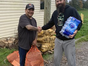 Trevor Bomberry, of Six Nations of the Grand River, one of the land defenders occupying the former Arrowdale golf course property, accepts a donation of firewood and bottled water from Josh Kraemer.