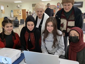 Pat Eyzenga (left) and Lucy Marco watch as Bylasan Hanana (left), Ranya Sharif, Fatma Eltaha and Eva Eltaha prepare a presentation during the Brantford Mosque's ninth annual open house on Saturday. Eyzenga and Marco were among the guests at the event, which included tours.