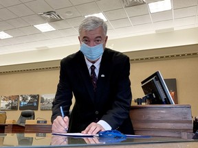 Brockville Mayor Mike Kalivas signs the declaration of the oath of office after being sworn in at City Hall on Friday afternoon. (RONALD ZAJAC/The Recorder and Times)