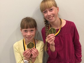 Sarah (left) and Alice Fehr with the medals they won for their categories at a regional spelling bee en route to competing in the national one earlier this month. Violet Fehr