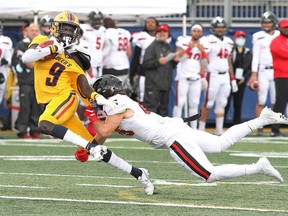 Queen's Gaels receiver Ajay Chol gets his jersey pulled by Carleton Ravens defender Cedrick Lavigne after catching a pass in Ontario University Athletics football action at Richardson Stadium in Kingston on Saturday.