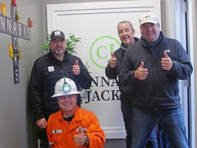 Cannabis Jacks owners Tom Laronde, left, John Shelegey, kneeling, and Steve Beaudry, right, give a thumbs up with founder Mike Birch, Thursday, at the business's official opening on Cassells Street. PJ Wilson/The Nugget
