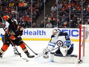 Mason McTavish #37 of the Anaheim Ducks skates the puck against Connor Hellebuyck #37 of the Winnipeg Jets in the second period at Honda Centre on Oct. 13 in Anaheim, California.