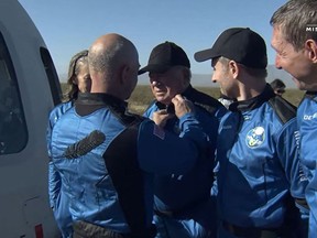 In this still image taken from a Blue Origin video, Blue Origin founder Jeff Bezos awards New Shepard NS-18 mission crew member "Star Trek" actor, William Shatner with a pin after the crew landed on Oct. 13, in the West Texas region, 25 miles (40kms) north of Van Horn. - The other members (L R) Blue Origins vicepresident of Mission & Flight Operations, Audrey Powers; Planet Labs co-founder, Chris Boshuizen and Medidata Solutions Co-Founder, Glen de Vries, also received a pin from Bezos,