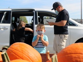 Rylan Braswell, 4, eyes a pumpkin while sister Blakley, 7, and dad Jesse get out of their van at the Lambton Central Petrolia Optimist Club's Great Pumpkin Giveaway event on Saturday October 2, 2021 in Petrolia, Ont. Terry Bridge/Sarnia Observer/Postmedia Network