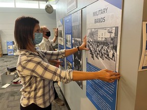 Nicole Aszalos, with the Lambton County Archives, and Don Vander Klok, with the Lambton Concert Band, hang panels in the lobby of the Sarnia Library Theatre for an exhibit about the history of community bands in Lambton County.