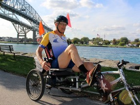 Peter Degraaf, 86, from Point Edward cycles near the Blue Water Bridge with U.S. and Canadian flags in the distance on Wednesday October 13, 2021 in Point Edward, Ont. The land border between the two countries is set to open next month to fully vaccinated Canadian travellers for non-essential trips for the first time since March 2020, the U.S. government announced this week. Terry Bridge/Sarnia Observer/Postmedia Network