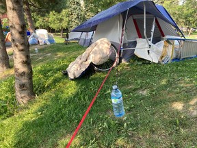 A water bottle dangles from a clothesline outside a tent in Memorial Park on a sweltering day last summer.