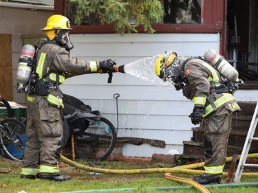 A firefighter sprays another with water to wash off debris and ashes at a fire at a three-unit apartment on Frood Road and Bloor Street in Sudbury, Ont. on Monday October 4, 2021. John Lappa/Sudbury Star/Postmedia Network