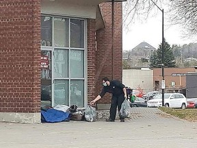 In this file photo, a passerby hands money to a homeless person camped out in front of the Sudbury Arena. City councillors are looking at ways to make life easier for Sudbury's homeless population.