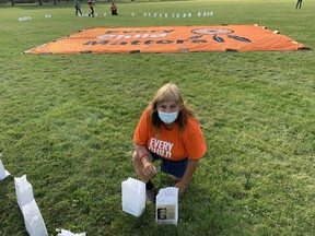 Terrylynn Brant decorates a luminary with a tribute to her father, James Walter Powless, who attended the Mohawk Institute residential school in Brantford from 1939 to 1950. The luminaries were used for a candlelight vigil Thursday at Chiefswood Park on Six Nations of the Grand River to mark the National Day of Truth and Reconciliation. Susan Gamble/Postmedia