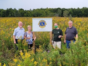 Lions Club representatives Paul DeCloet and Josiane DeCloet stand with NCC staff members Liv Monck-Whipp and Ron Keba in front of a sign to commemorate the Lions Club centennial tree planting project at Backus Woods. (Nature Conservancy Canada photo)