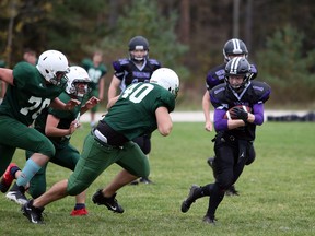 Running back Tyler Jack protects the ball in the first quarter with Grey Highlands Lions defender Nathan DiMichelle (40) in pursuit as the OSDSS Wolves and Grey Highlands Lions play their Bluewater Athletic Association regular season opener in Flesherton Friday afternoon. Greg Cowan/The Sun Times