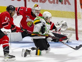 Harassed by Owen Sound Attack defender Cedricson Okitundu, London Knights forward Ever Barkey manages to get off a shot as he slides past net minder Mack Guzda in the first period of their OHL game at Budweiser Gardens in London, Ont. on Friday October 8, 2021. Guzda stretched and stopped the puck with his toe. Derek Ruttan/The London Free Press/Postmedia Network