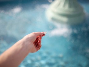 Woman's Hand Throwing Coin in Wishing Fountain