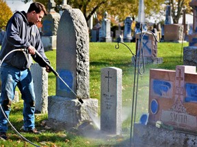 Chris Tudor, Campbell Monuments field services lead hand, power washes blue paint from a Canadian military veteran gravestone, one of eight military monuments vandalized at St. James Roman Catholic Cemetery in Belleville this week. Tudor said it was important to restore gravestones before Remembrance Day Nov. 11. DEREK BALDWIN