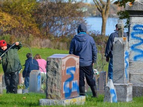 A Campbell Monument field worker uses a pressure washer and detergent to remove spray paint from a desecrated gravestone at St. James Roman Catholic Cemetery in Belleville where 350 grave markers were defaced over two nights earlier this month. Police continue to search for the vandals. DEREK BALDWIN