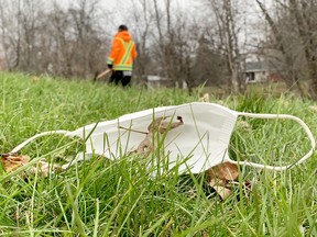 A discarded face mask lies among the autumn leaves while a worker is seen on the Brock Trail near Central Avenue in Brockville on Thursday, Nov. 25, 2021. (RONALD ZAJAC/The Recorder nd Times)