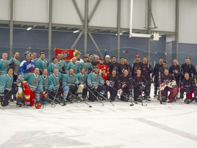 The Airdrie RCMP and Fire Department teams pose together on the ice at the annual charity hockey game. (Photo by Kelsey Yates/Airdrie Echo/Postmedia Network)