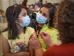 Sofia Flores Rojas, 9, sits with her mom Alejandra as she receives a COVID-19 vaccine in Calgary on November 26, 2021. Leah Hennel / AHS