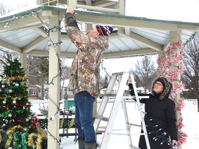 Rick Leblanc and Ginette Trottier string up lights outside the Howard Armstrong Recreation Centre on Sunday.