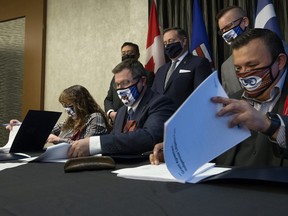 Premier Jason Kenney (back centre) watches as (L-R) Willow Lake Métis Nation president Stella Lavalee, Indigenous Relations Minister Rick Wilson, and Fort McKay Métis Nation president Ron Quintal sign an agreement that will see the Alberta Government provide a $372,000 grant to support the two Métis organizations in their fight against Bill C-48, in Edmonton Monday Nov. 15, 2021. Photo by David Bloom
