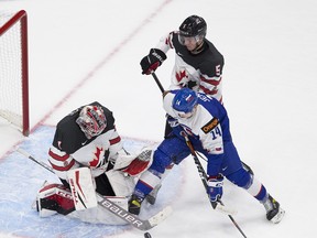 Canada's goalie Devon Levi (1) stops the puck with teammate Thomas Harley (5) as Slovakia's Dominik Jendek (14) can't get the puck during second period IIHF World Junior Hockey Championship action on Sunday, Dec. 27, 2020 in Edmonton.